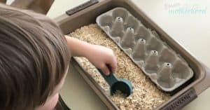 Child playing with sensory bin containing oats