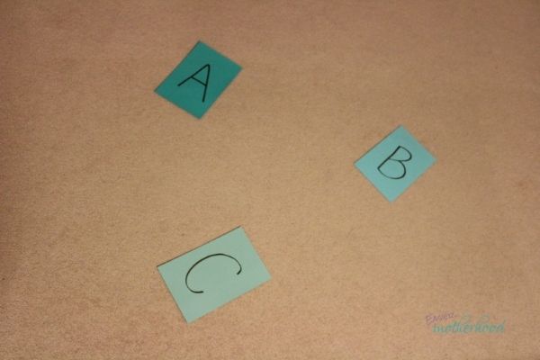 Colored cardstock paper with letters A, B, and C written on them and placed apart for a preschooler to jump to.