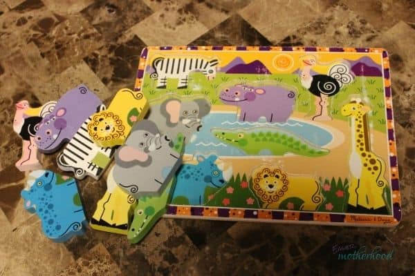 Wood Animal Puzzle on a coffee table with the pieces askew out of the board, right before the pieces are to be hidden for a preschool scavenger hunt.