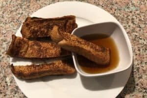 Image depicts how french toast- a kid friendly meal- can be made utensil free by cutting it into thirds to make dippable french toast sticks.