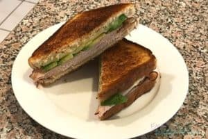 This photo shows a white plate with a turkey melt cut in half on it, one of the easy kid friendly meal ideas on this list.