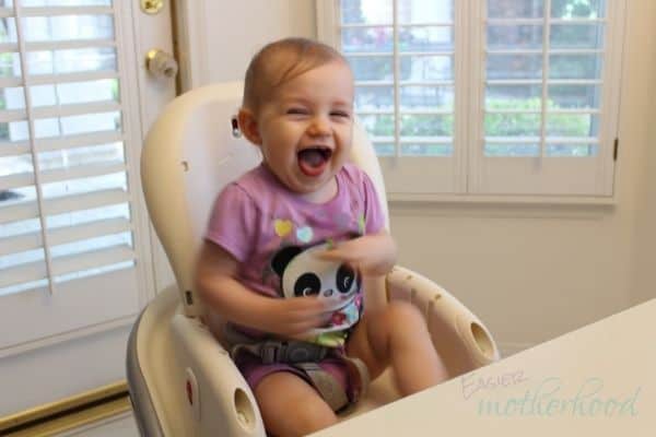 Little girl laughing in high chair