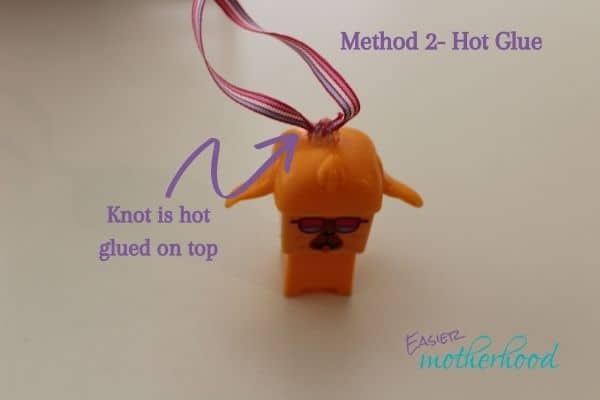 Image illustrating how to turn a toy into a Christmas ornament using the hot glue method- finished toy has arrow showing the hot glue and knot sitting on top of the toy.