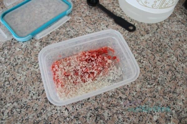 Red dye and vinegar in container with rice, before shaking to dye it.