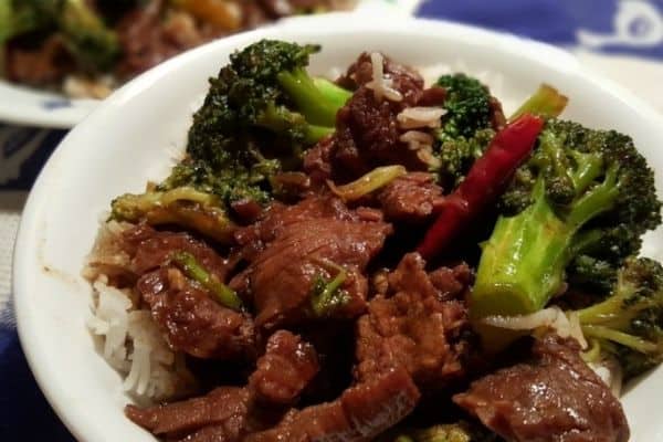 A white plate with slow cooker beef and broccoli served over rice.