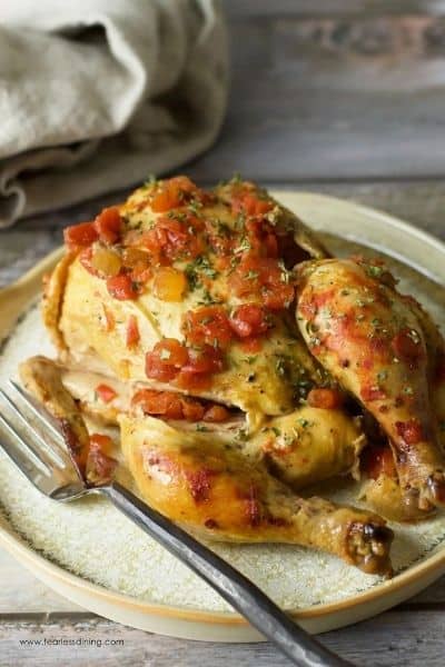 Slow Cooker Cornish Hen with tomato sauce on top on a white plate with a fork