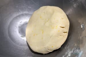 Dough formed into a large puck sitting in the bowl ready to refrigerate