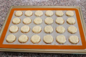 24 shaped cookies on a silicone mat on a cookie sheet ready to bake