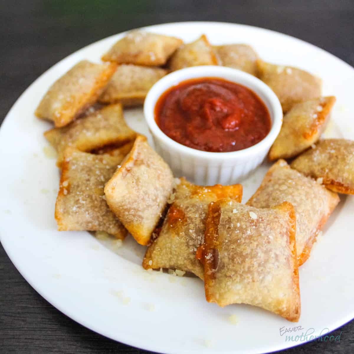 Air Fryer Pizza Rolls on a white plate dusted with parmesan cheese with pizza sauce on the side