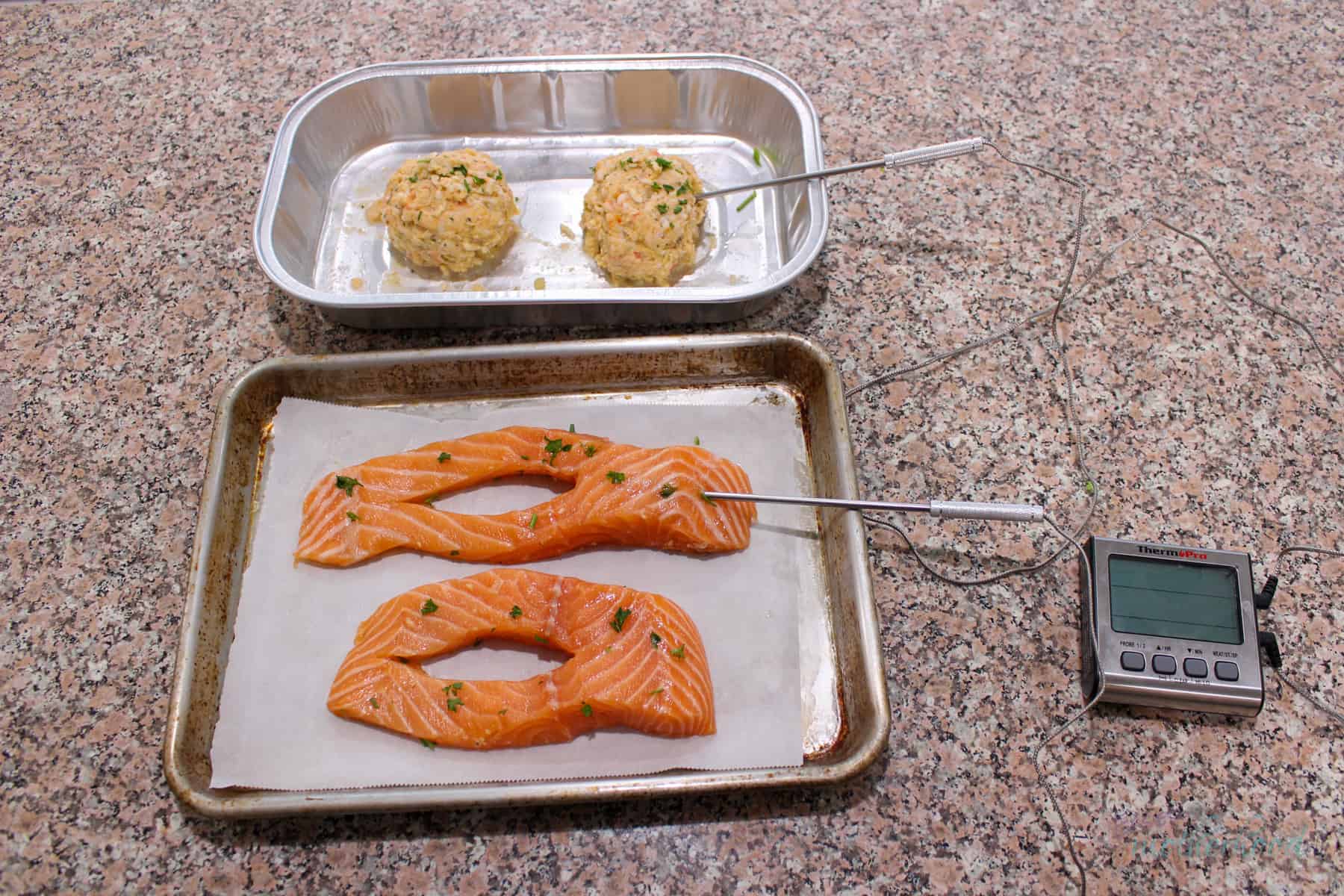 Salmon on baking sheet and stuffing in original container with temperature probes in one of each