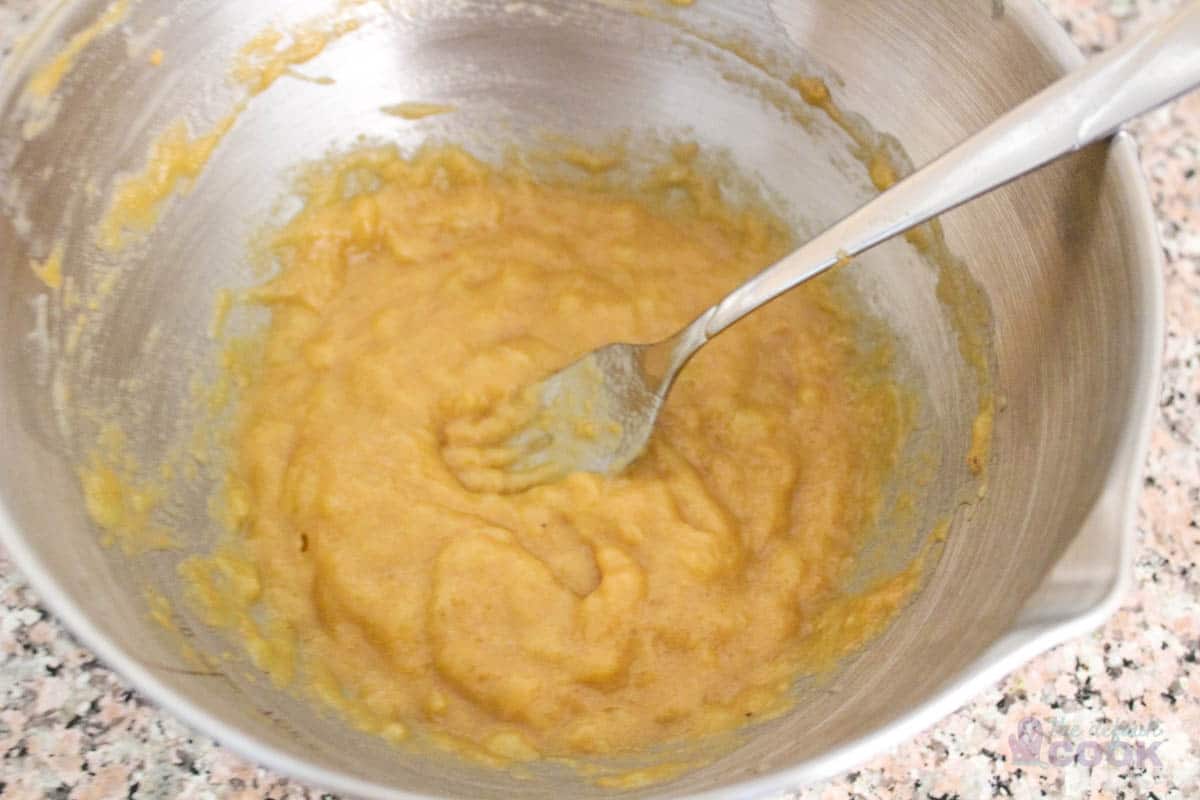 Maple syrup, peanut butter, and mashed banana mixed in a bowl with a fork.