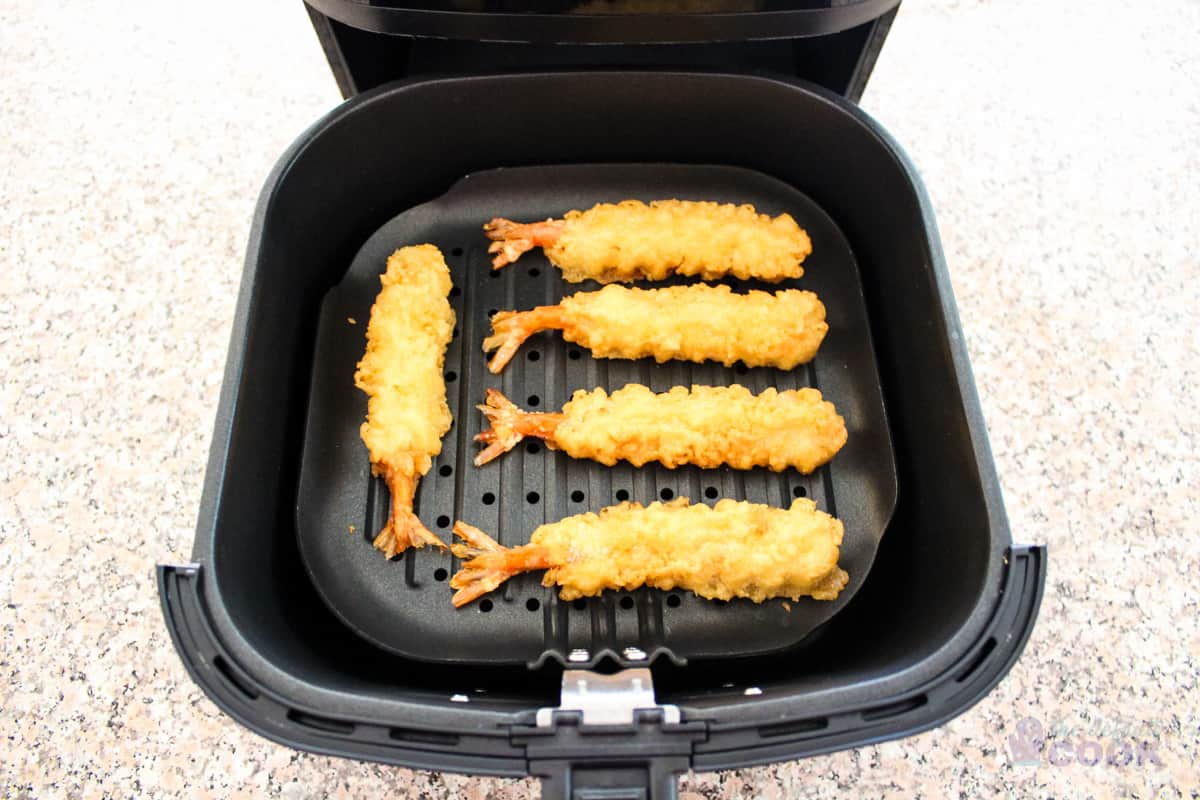 5 tempura shrimp on an air fryer grill pan, spread out so they do not touch each other.