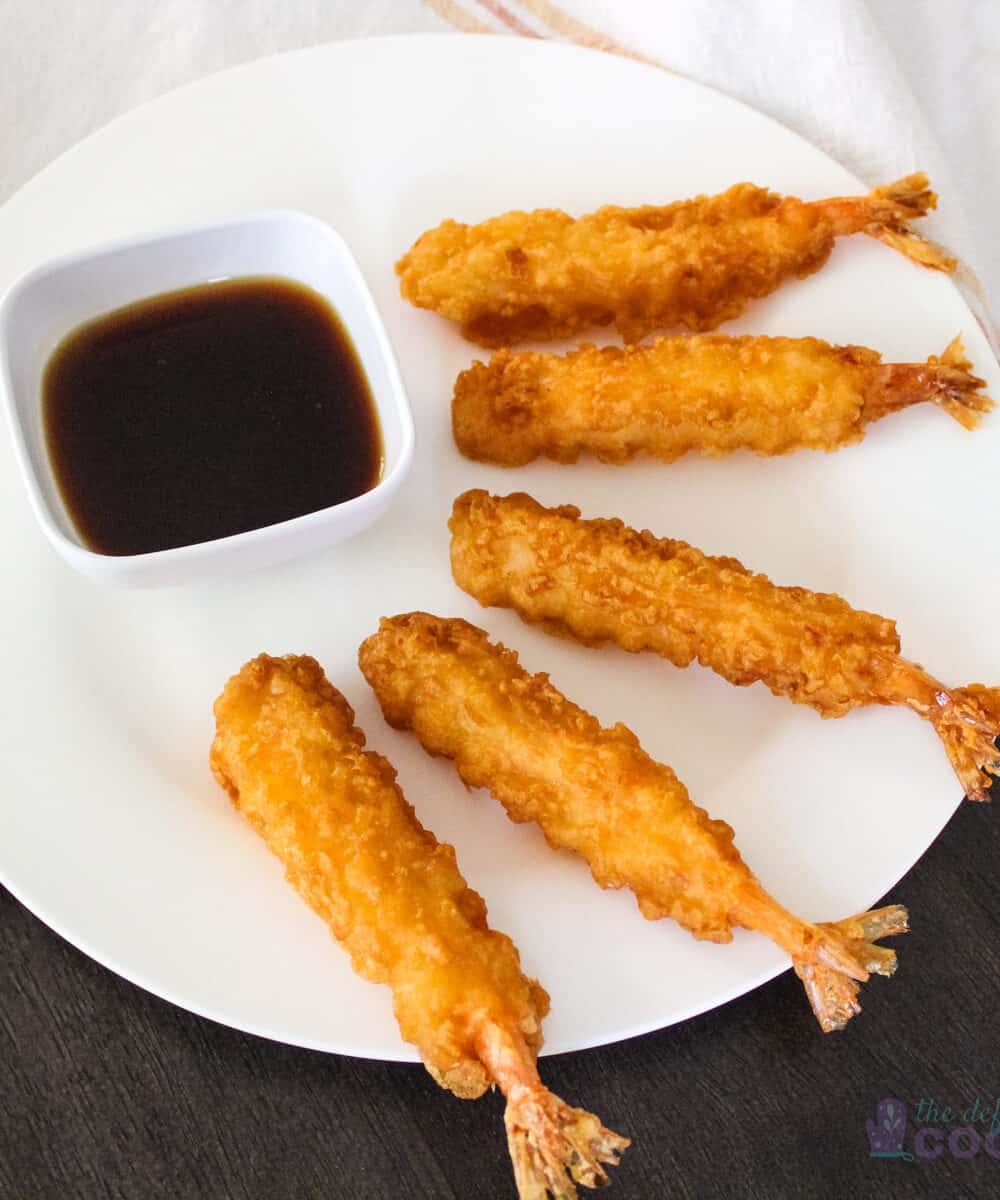 5 tempura shrimp on a white plate with sauce in small dipping bowl