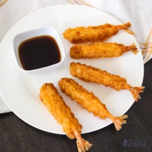 5 tempura shrimp on a white plate with sauce in small dipping bowl