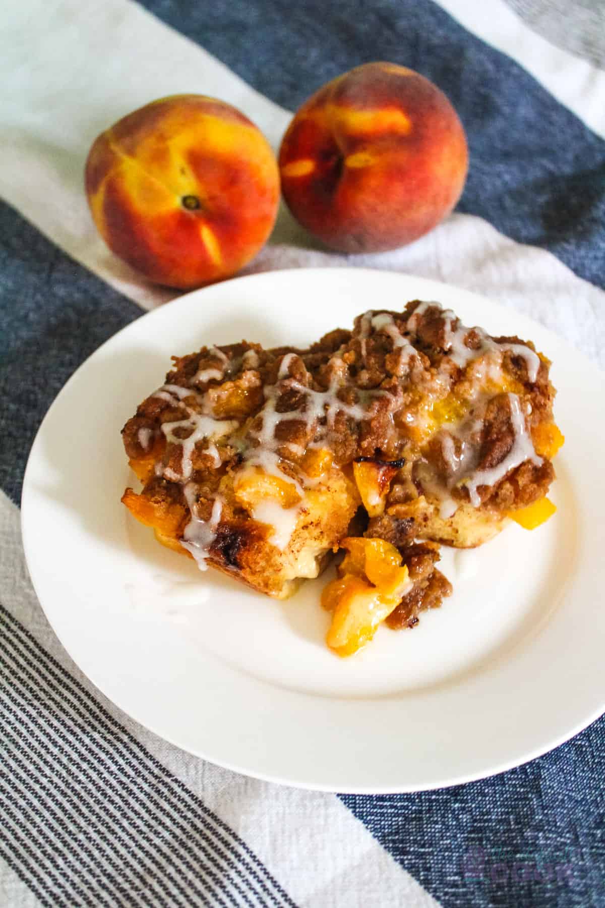 Two peach cobbler cinnamon rolls on a white plate.