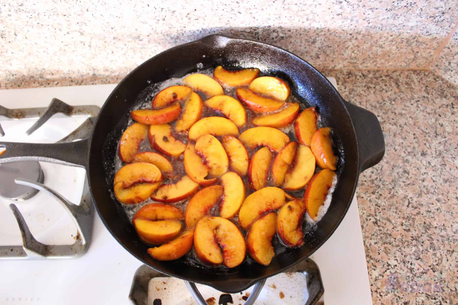 Peaches cooking in skillet on gas range