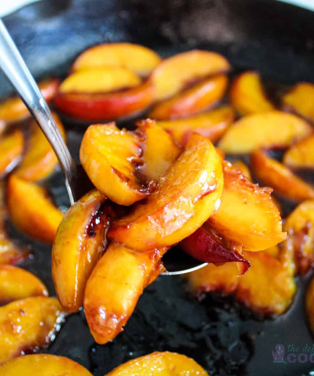 Close up of caramelized peaches on serving spoon with more in background