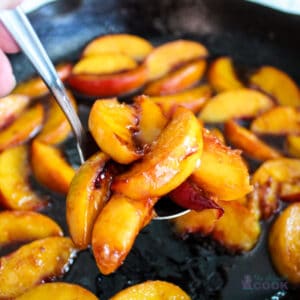 Close up of caramelized peaches on serving spoon with more in background