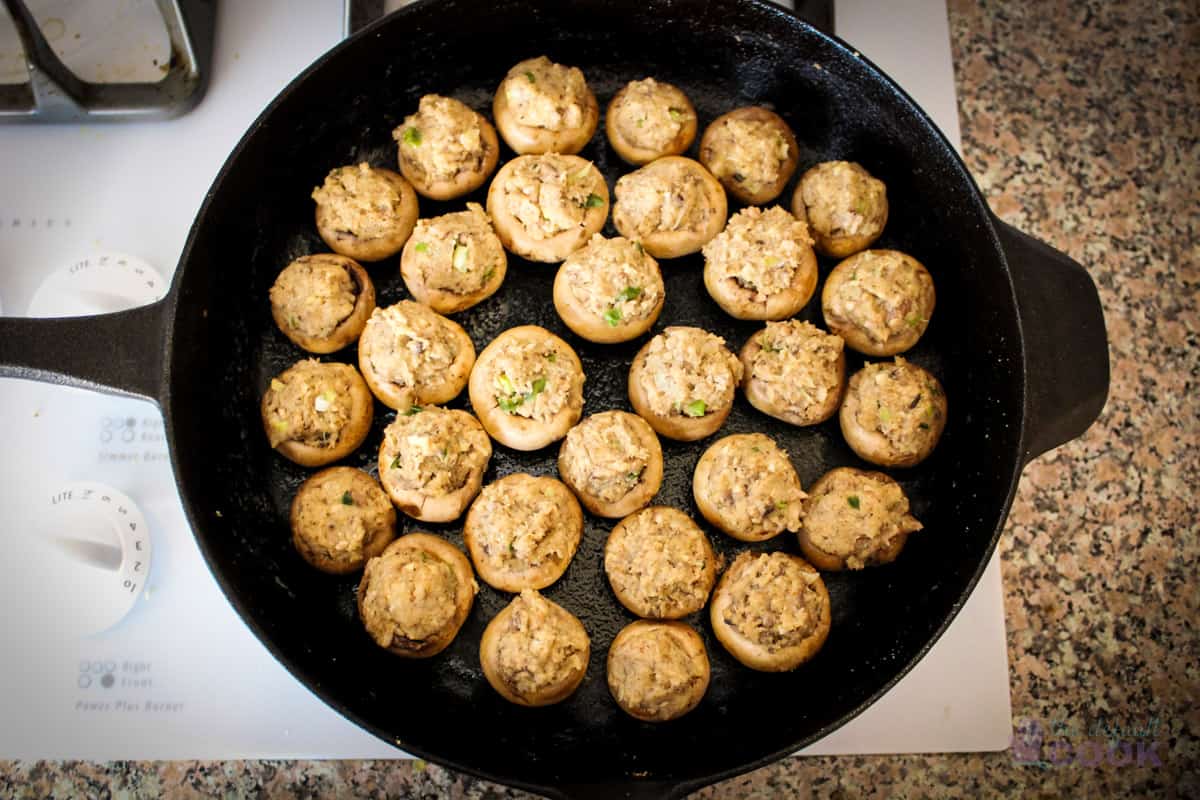 Skillet with prepared stuffed mushrooms ready to bake.