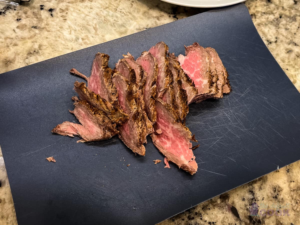 Sliced tri tip on a flexible cutting board.