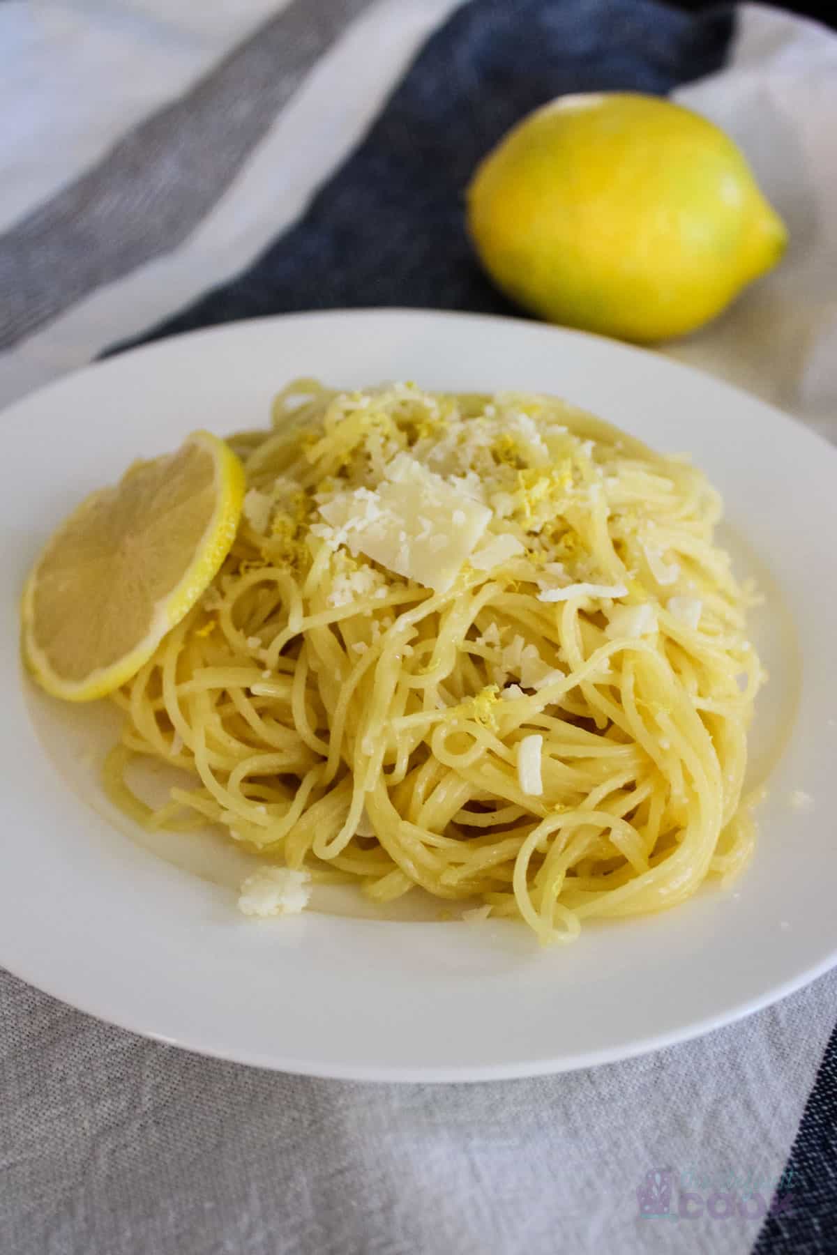 Lemon butter garlic pasta on a white plate with a blue and white background.