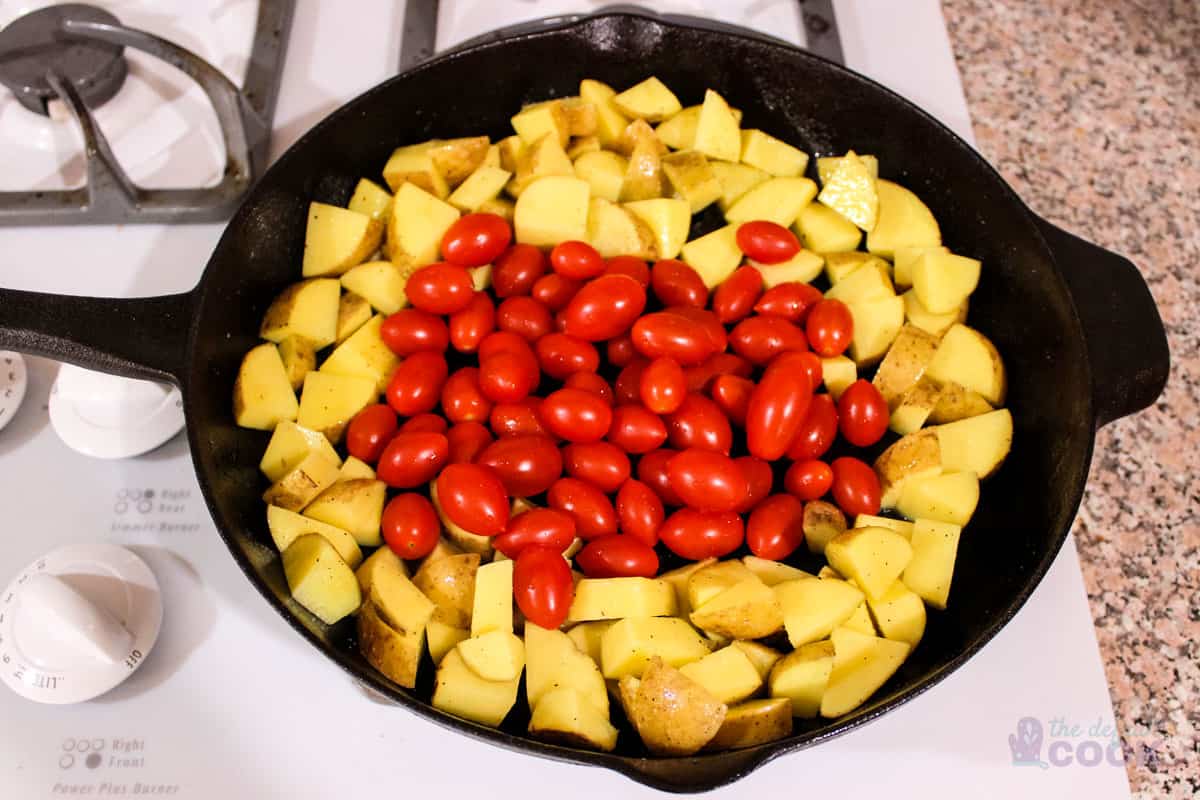 Potatoes and tomatoes ready to cook in skillet.