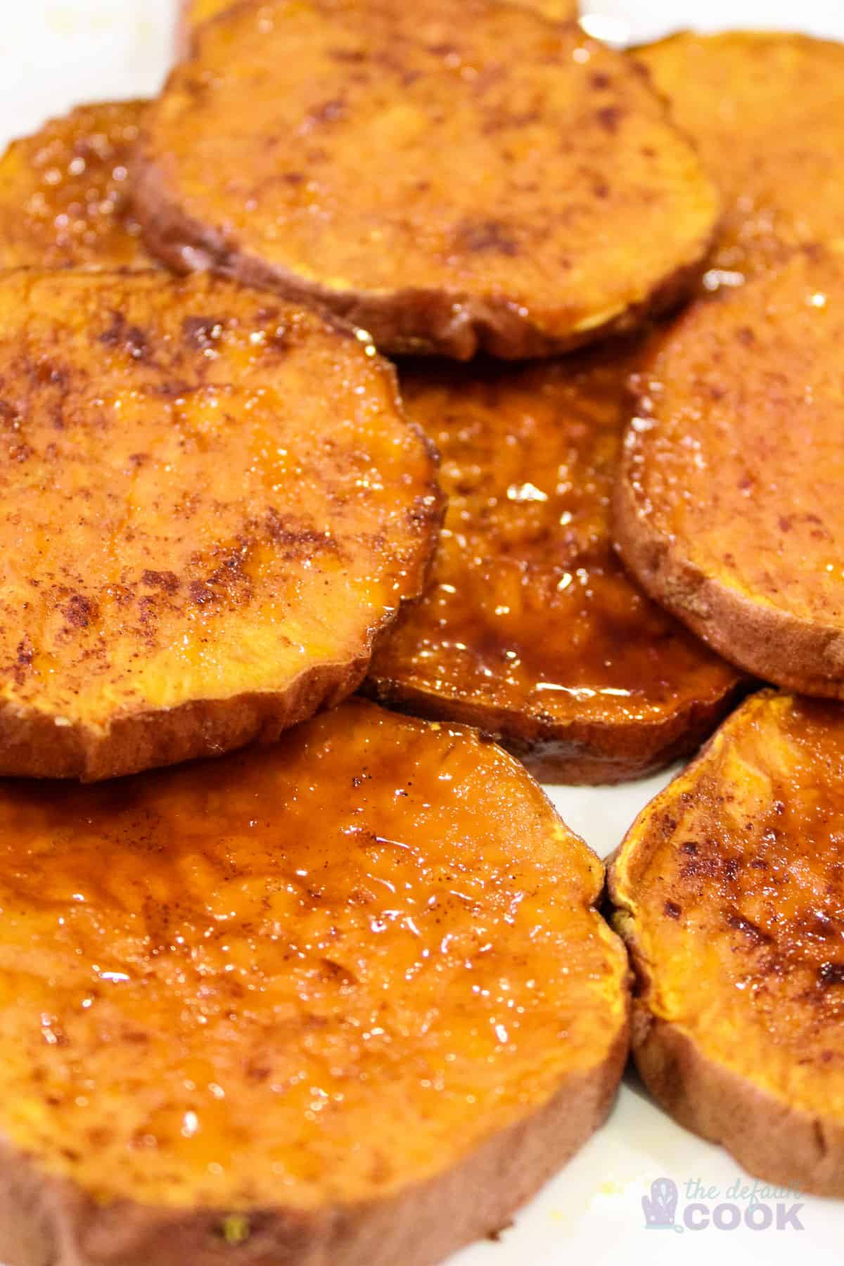 Close up of roasted sweet potato rounds on a white plate.