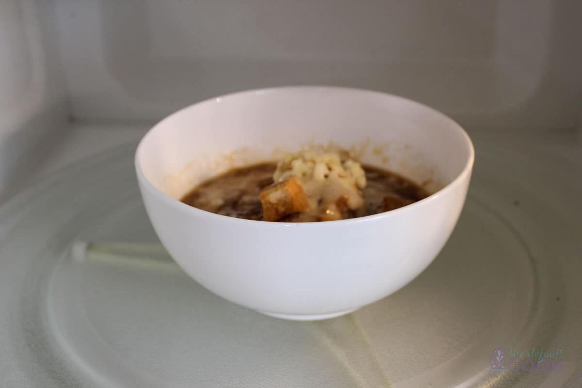 Bowl of soup halfway cooked in microwave.