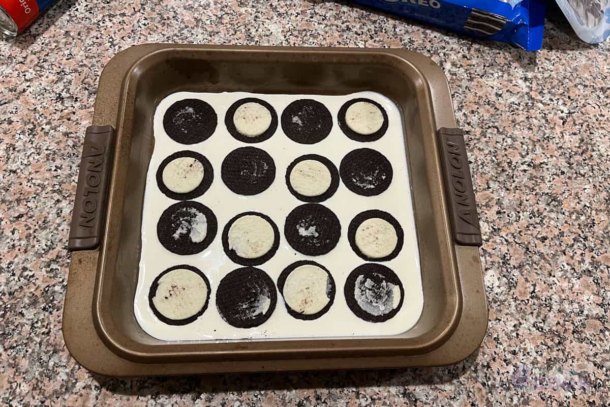 Baking pan with cream in it along with 8 disassembled cookies.