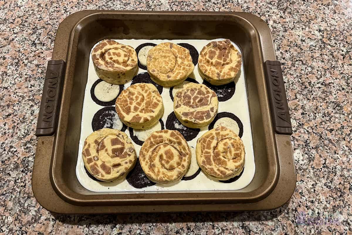 Baking pan with raw cinnamon rolls on top of oreo halves and heavy cream.