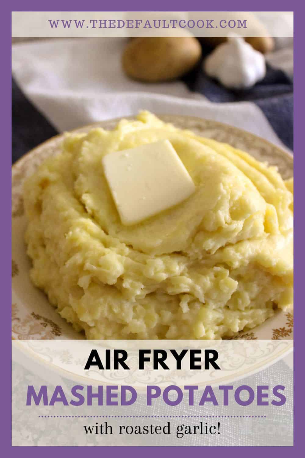 Mashed potatoes on a plate with butter melting on them, and uncooked potatoes and garlic in the background.