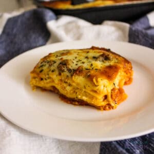 Serving of Costco Lasagna on a white plate with rest of tray in background.