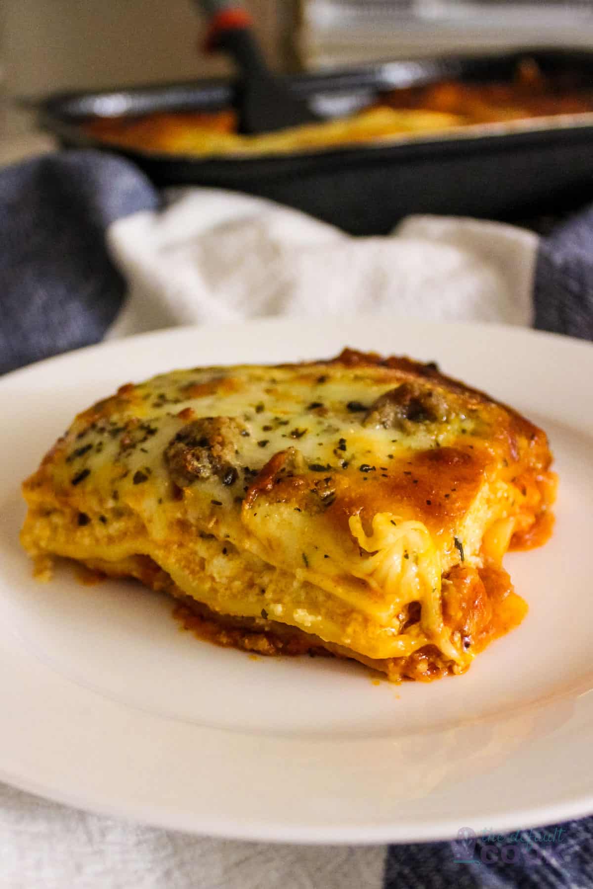 Serving of Costco Lasagna on a white plate with rest of tray in background.