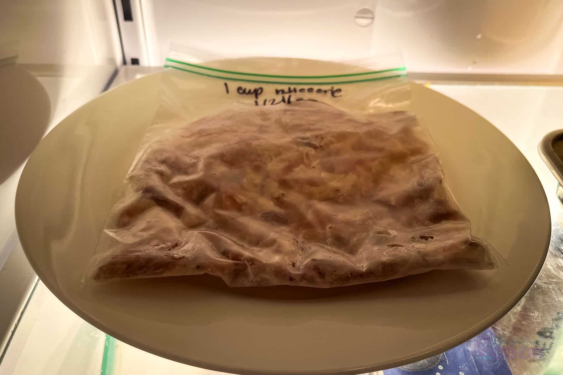 Frozen rotisserie chicken sitting on a plate in the fridge.