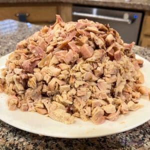 A pile of diced rotisserie chicken on a plate in a kitchen.