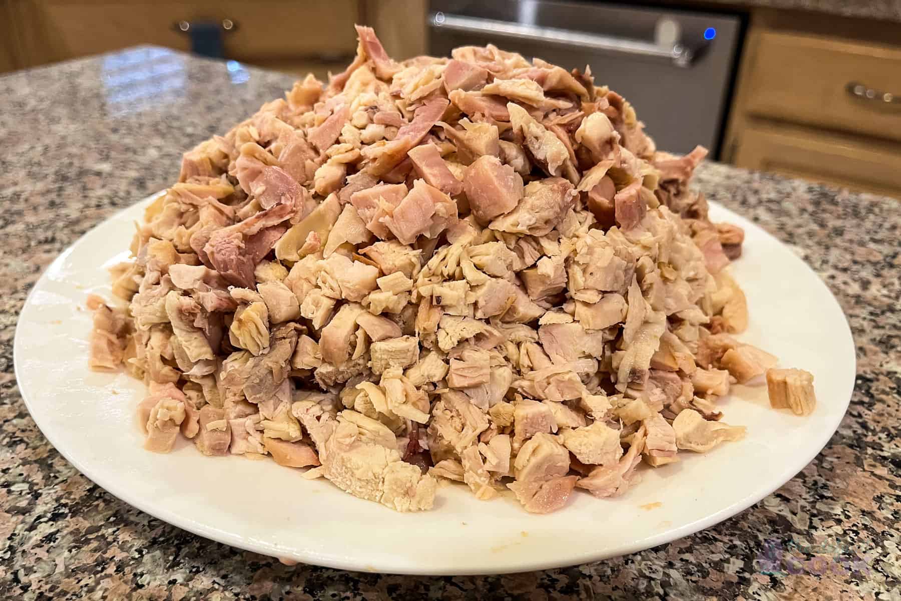 A pile of roughly diced rotisserie chicken on a plate.