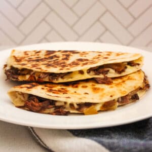 Two quesadillas stacked on a white plate.