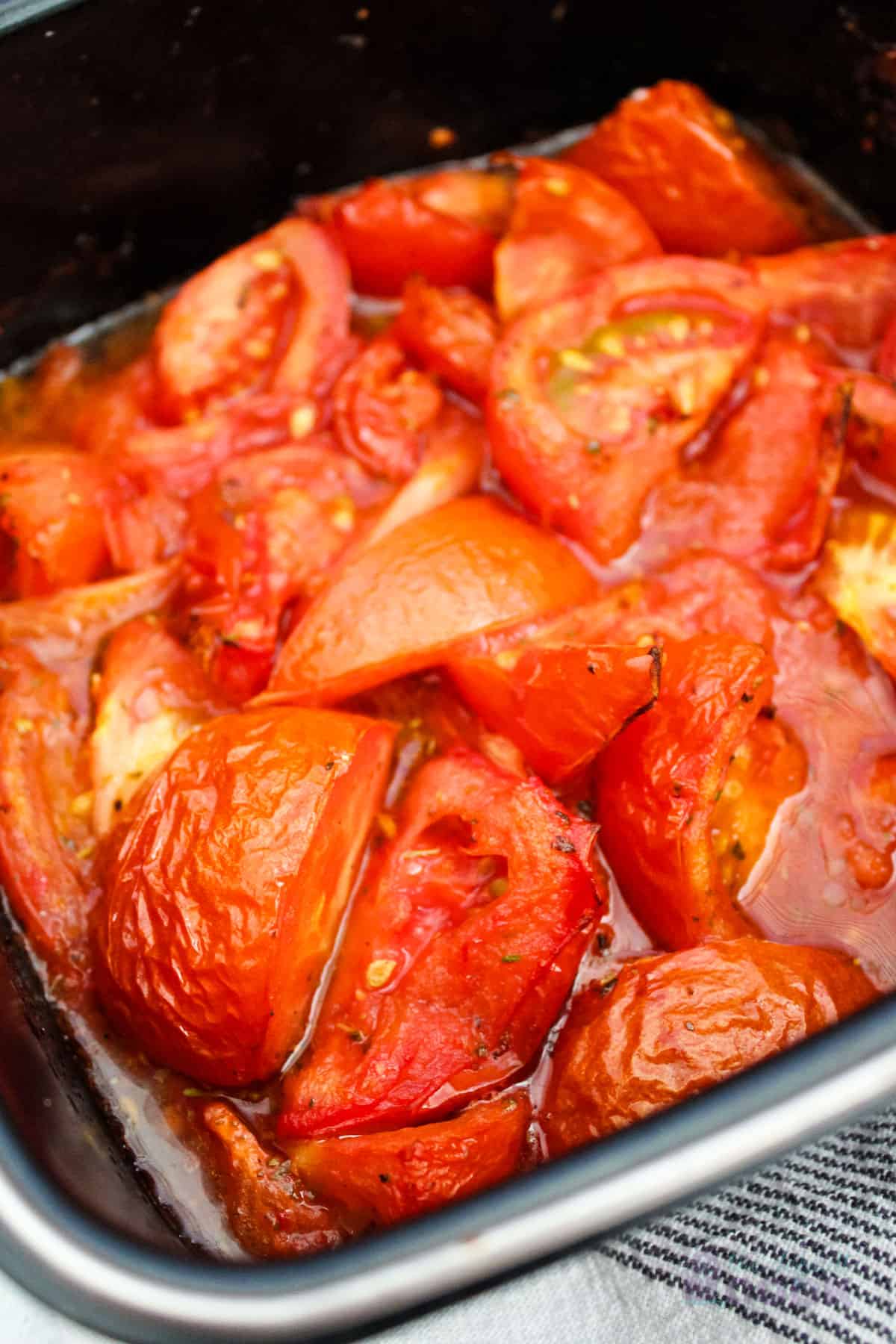 Close-up of a baking dish with roasted tomatoes inside.