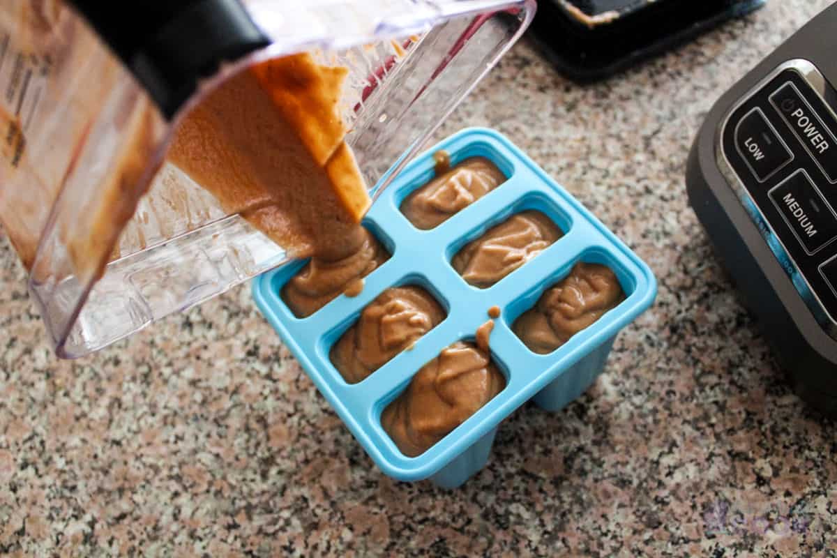 Pouring banana mixture into popsicle mold.