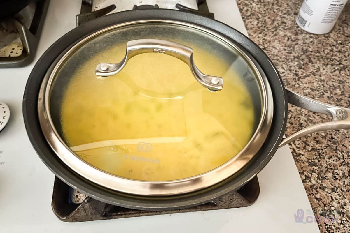 Scrambled egg mixture in a skillet cooking with a lid on top.