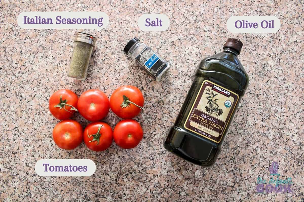 Tomatoes, olive oil, salt, and italian seasoning on a kitchen counter.