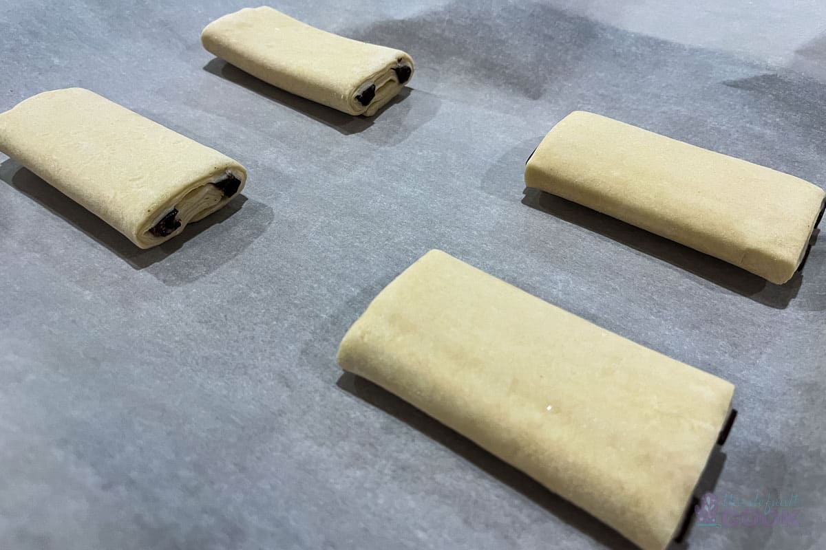 4 frozen croissants on a parchment paper lined baking tray to rise.