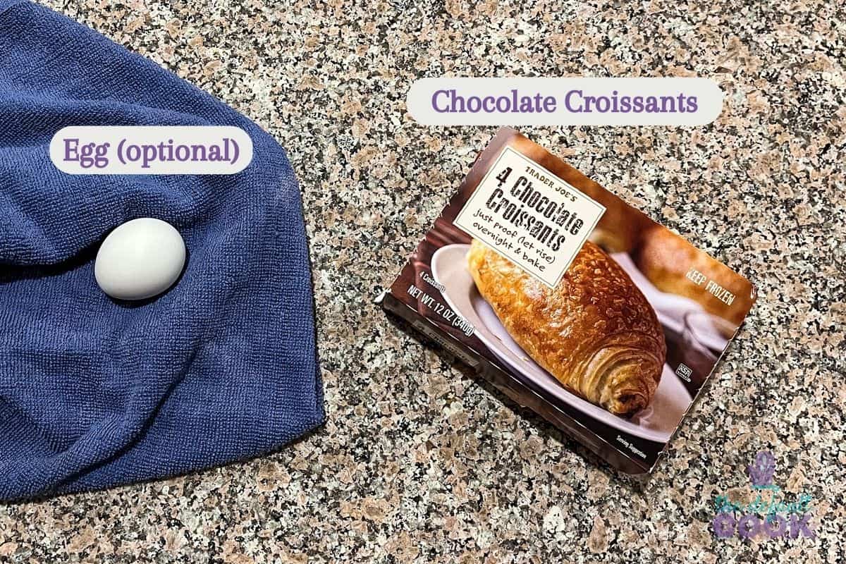 A box of frozen chocolate croissants and an egg on a countertop.