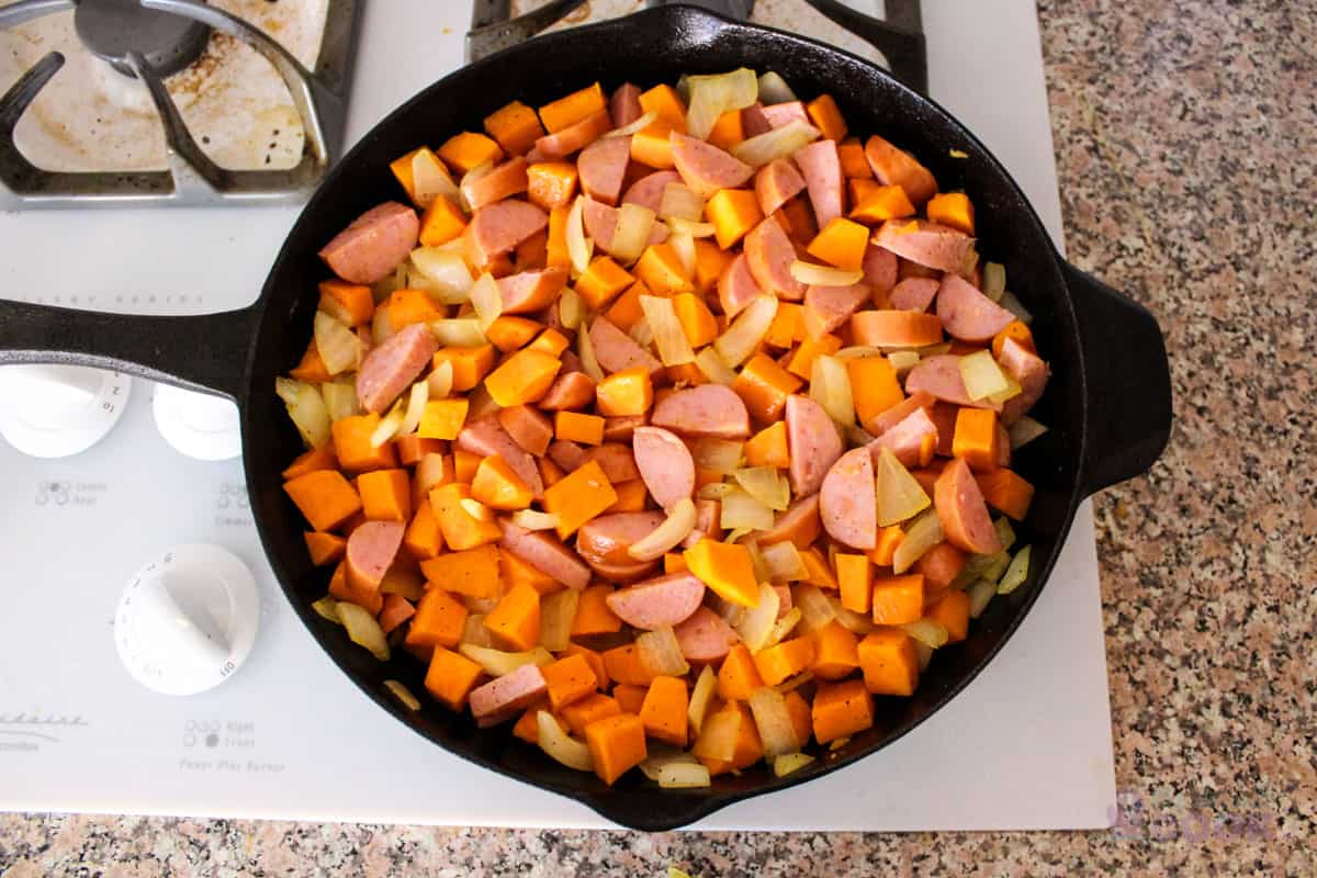 Skillet with the sausage added to the onions and potatoes.