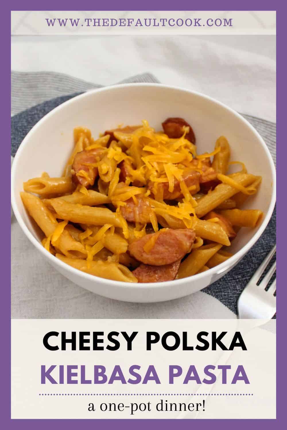 Bowl of kielbasa pasta topped with cheddar cheese, text below is "cheesy polska kielbasa pasta".