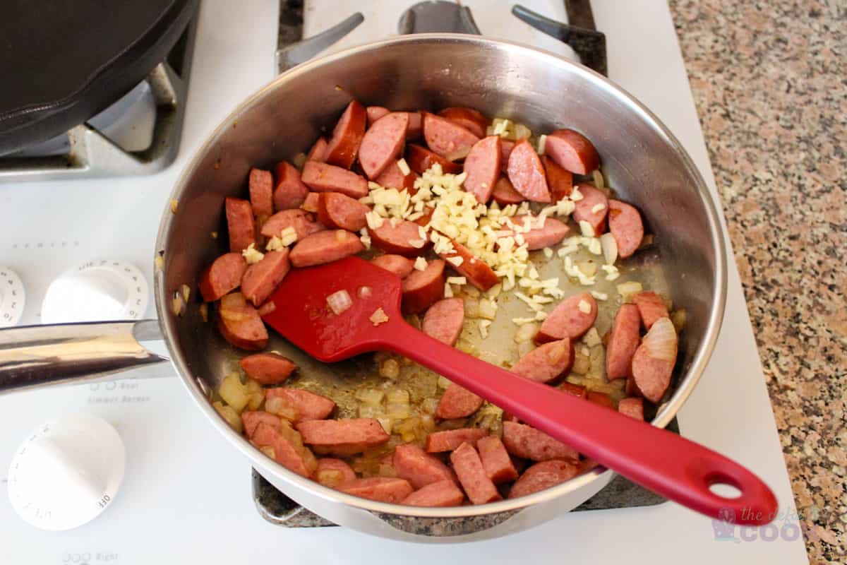 Saute pan with browned onions and sausage, garlic just added.