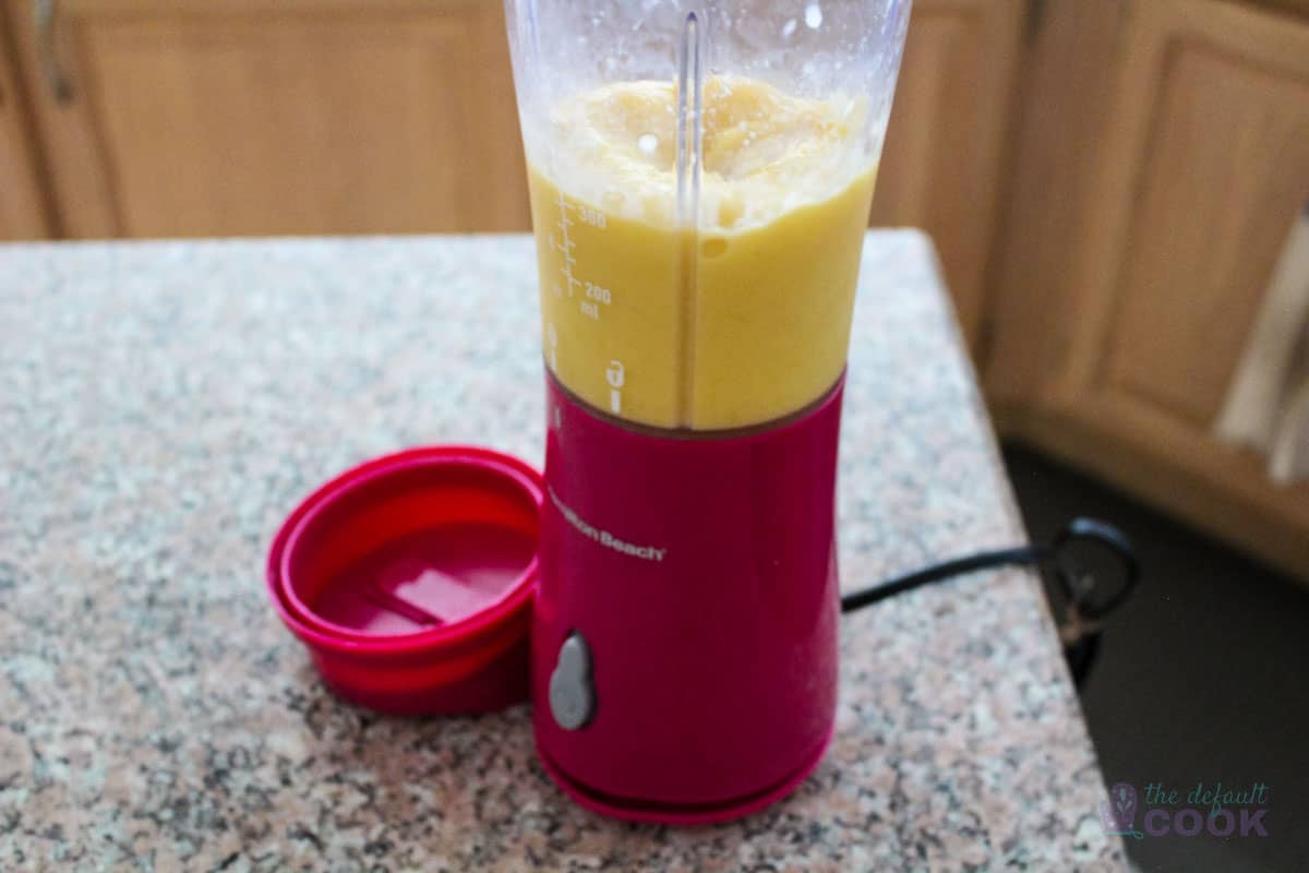 Small blender with pureed mango inside after blending.