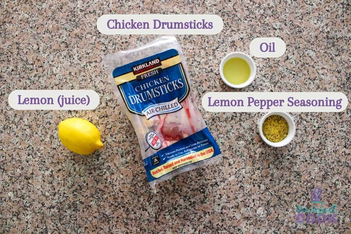 Labeled ingredients on a kitchen counter: lemon (for juice), chicken drumsticks, oil, and lemon pepper seasoning.