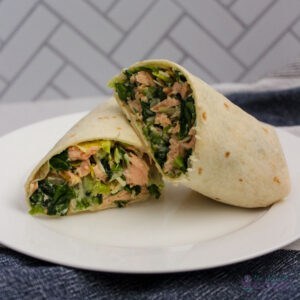 Salmon wrap sliced in half with one half leaning on the other on a white plate.