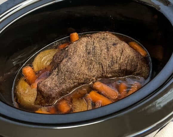 Finished tri tip roast in a slow cooker on a bed of carrots and onions.